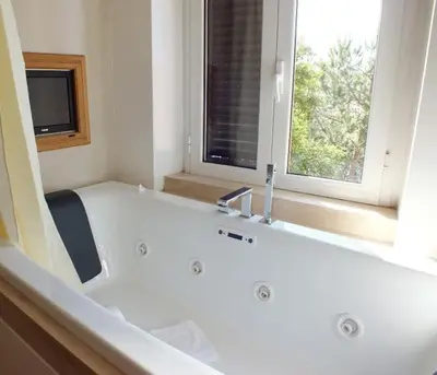 a white bathroom with a tub and a tv at Vatican Garden House in Rome
