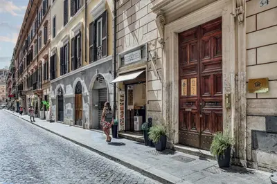 a woman walking down a street next to a building at Spagna Dream Suites in Rome