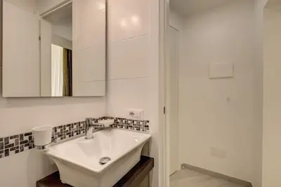a white bathroom with a sink and a mirror at Dimore Costaguti in Rome