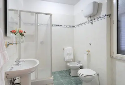 a white bathroom with a toilet and a sink at Hotel Oriente in Rome