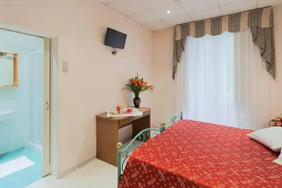 a bedroom with a red bed and a tv on the wall at Hotel Oriente in Rome
