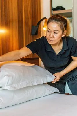 a woman is making a pillow on a bed at Gasometer Urban Suites in Rome