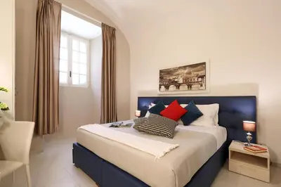 a bedroom with a large bed with red pillows at Grand Tour Rome Apartment - Liberty Collection in Rome