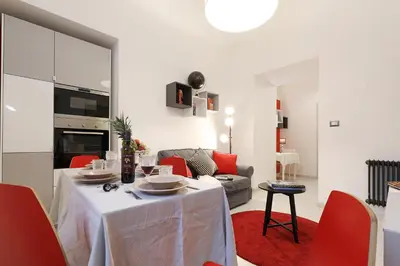 a living room with a table and red chairs at Grand Tour Rome Apartment - Liberty Collection in Rome