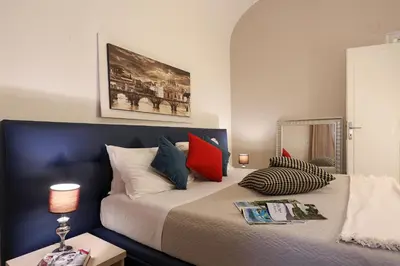 a bedroom with a large bed with red and blue pillows at Grand Tour Rome Apartment - Liberty Collection in Rome
