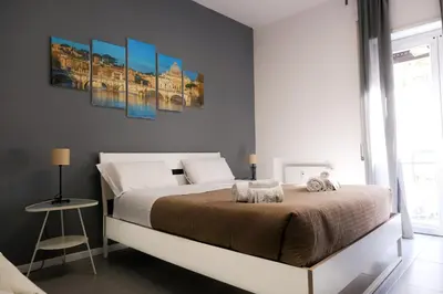 a bedroom with a large bed with two paintings on the wall at Vatican Central Suites in Rome