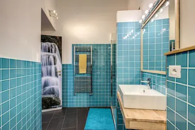 a blue tiled bathroom with a sink and a shower at Cavour Colloseum suite in Rome