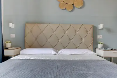 a bed with a padded headboard and two night stands at Holiday Sunny Roma B&B in Rome