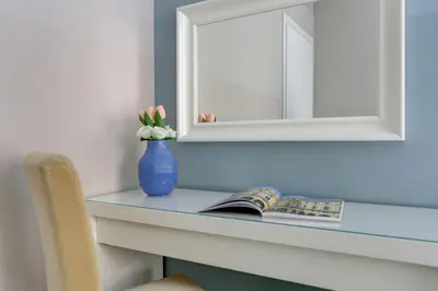 a blue vase with flowers on a desk with a mirror at Holiday Sunny Roma B&B in Rome
