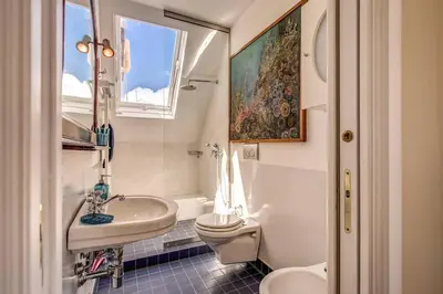a bathroom with a sink and a toilet and a window at Attic with Terrace Overlooking St Peter's Basilica in Rome