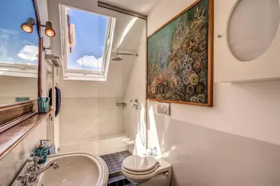 a bathroom with a sink toilet and a painting on the wall at Attic with Terrace Overlooking St Peter's Basilica in Rome