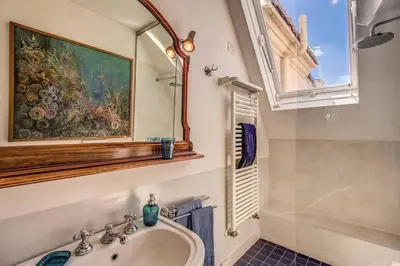a bathroom with a sink and a painting on the wall at Attic with Terrace Overlooking St Peter's Basilica in Rome
