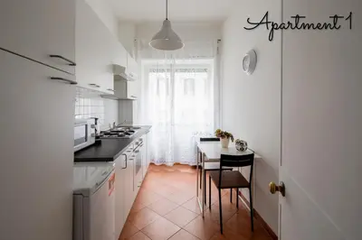 a kitchen with white cabinets and a table with chairs at PennyLane Rome Apartment in Rome