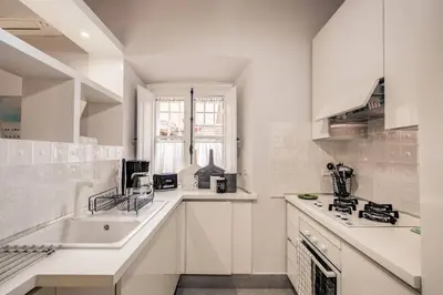 a white kitchen with a sink and a counter at Flat with terrace by Vatican in Rome