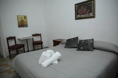 a bedroom with a bed with white sheets and chairs at B&B Bel Ami in Rome