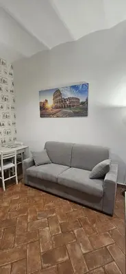 a couch in a living room with a painting on the wall at 50 Passi Colosseo Apartment in Rome