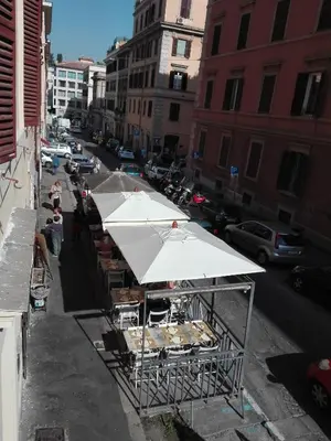 a food stand with white umbrellas on a city street at 50 Passi Colosseo Apartment in Rome