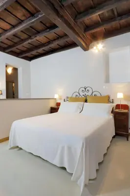a bedroom with a large white bed with wooden ceilings at Sangallo Rooms - Residenze Romanae in Rome