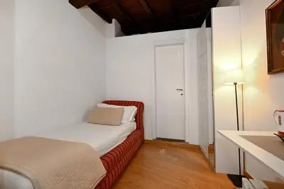 a small bedroom with a bed and a white door at Sangallo Rooms - Residenze Romanae in Rome