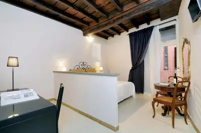 a bedroom with a bed and a table and a chair at Sangallo Rooms - Residenze Romanae in Rome