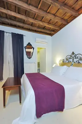 a bedroom with a large white bed and a wooden ceiling at Sangallo Rooms - Residenze Romanae in Rome