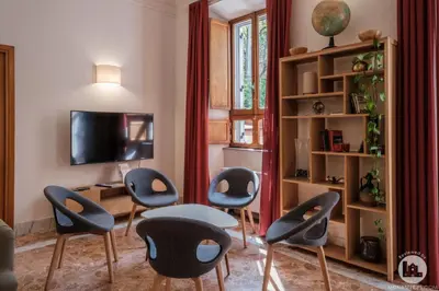 a living room with chairs and a table and a tv at Hotel Casa Valdese Roma in Rome