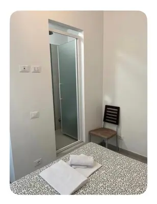a bathroom with a mirror and a bed and a chair at Les Artes in Rome