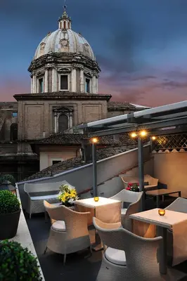 a rooftop patio with tables and chairs in front of a building at Hotel Lunetta in Rome