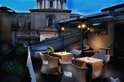 a rooftop patio with tables and chairs and a building at Hotel Lunetta in Rome