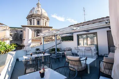 a balcony with tables and chairs and a building at Hotel Lunetta in Rome