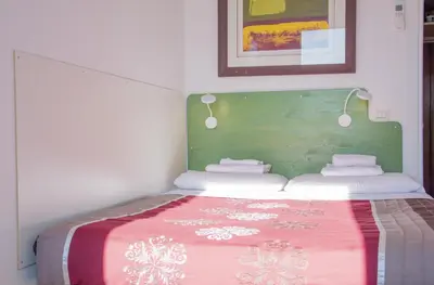 a small bedroom with a bed with a green headboard at BEACHBAR Apartment in Rome in Rome