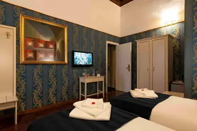 a bedroom with two beds and a tv on the wall at Canova Rooms in Spanish Steps in Rome