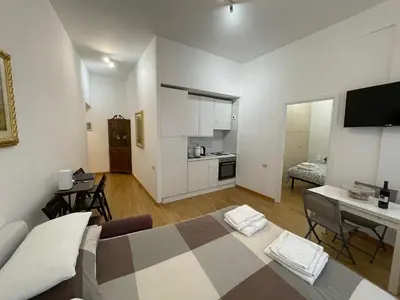 a room with a bed and a desk and a kitchen at Foro Romano Apartments B in Rome