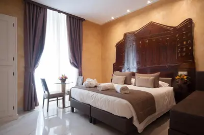 a bedroom with a large bed with a large wooden headboard at Maison Tritone in Rome