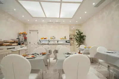a dining room with white tables and white chairs at Maison Tritone in Rome
