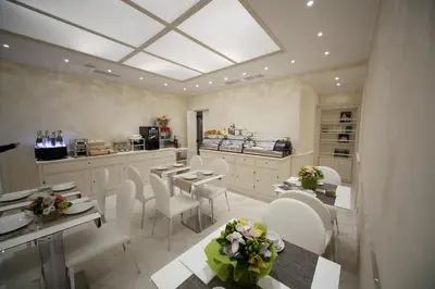 a dining room with tables and chairs and a kitchen at Maison Tritone in Rome