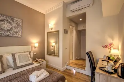 a bedroom with a bed and a desk and a mirror at Chester Suites in Rome