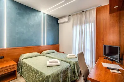 a hotel room with two beds and a desk and a television at Hotel Millerose in Rome
