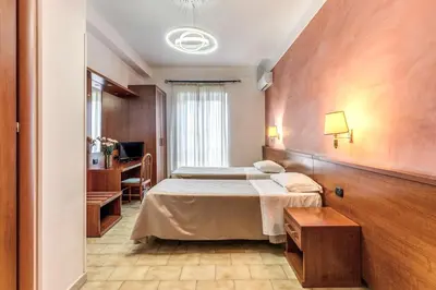 a hotel room with two beds and a desk at Hotel Millerose in Rome
