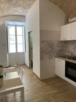 a kitchen with white cabinets and a table and a counter top at Campani Luxury Flat in Rome