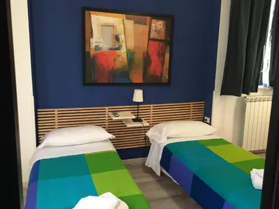 two beds in a room with a blue wall at Almi Rooms in Rome