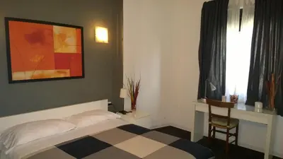 a bedroom with a bed and a chair and a window at Almi Rooms in Rome