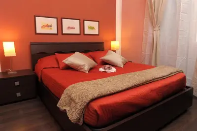 a bedroom with a bed with red sheets and two lamps at B&B Alexander in Rome