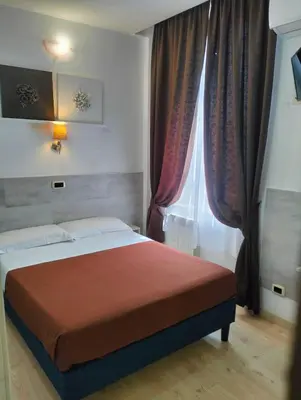a bedroom with a bed and a window with curtains at Hotel Indipendenza in Rome