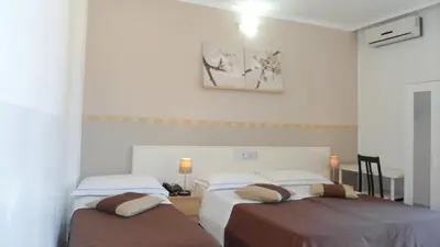 two beds in a room with white walls at Hotel Indipendenza in Rome
