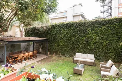 a garden with a couch and chairs and a hedge at Amazing 4 bedrooms apartment with garden in Rome