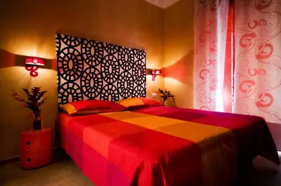 a bedroom with a bed with a red and orange blanket at Domus Diana in Rome