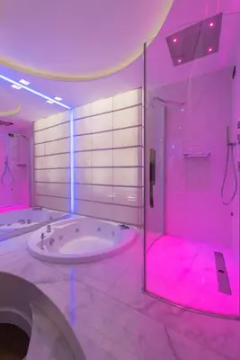 a bathroom with a tub and a shower with pink lights at LUX Suites in Roma in Rome