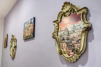 a gold mirror hanging on a wall with pictures at Royal Vatican in Rome