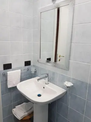 a white bathroom with a sink and a mirror at Chiara Rooms in Rome